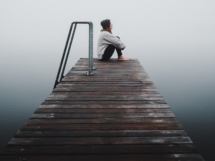 Nachdenkliche Person auf einem Steg als Symbol für innere Klärung